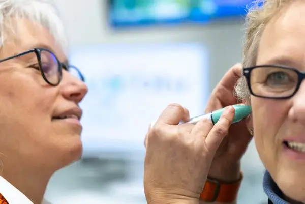 Hörtest beim Hörakustiker: Frau misst Ohr mit modernem Gerät im Hörakustik-Fachgeschäft.