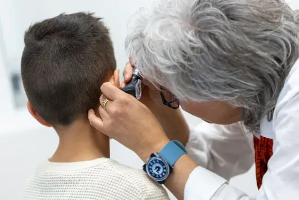 Ärztin untersucht das Ohr eines Jungen bei einer kinderärztlichen Vorsorgeuntersuchung.